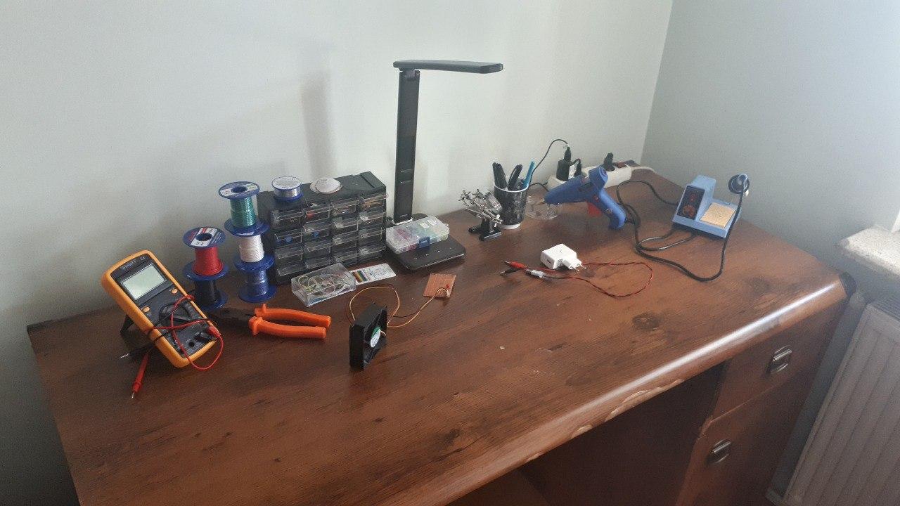 A desk with soldering iron, multimeter and electronic components on it